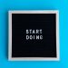 Black letter board with 'START DOING' text on a vibrant blue background.