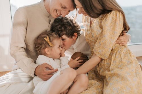 A happy family of four sitting together and sharing a loving moment indoors.